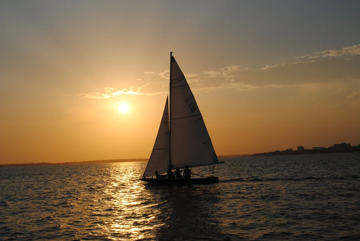 Sailboat silhouetted against the sun on a Charleston harbor sunset cruise