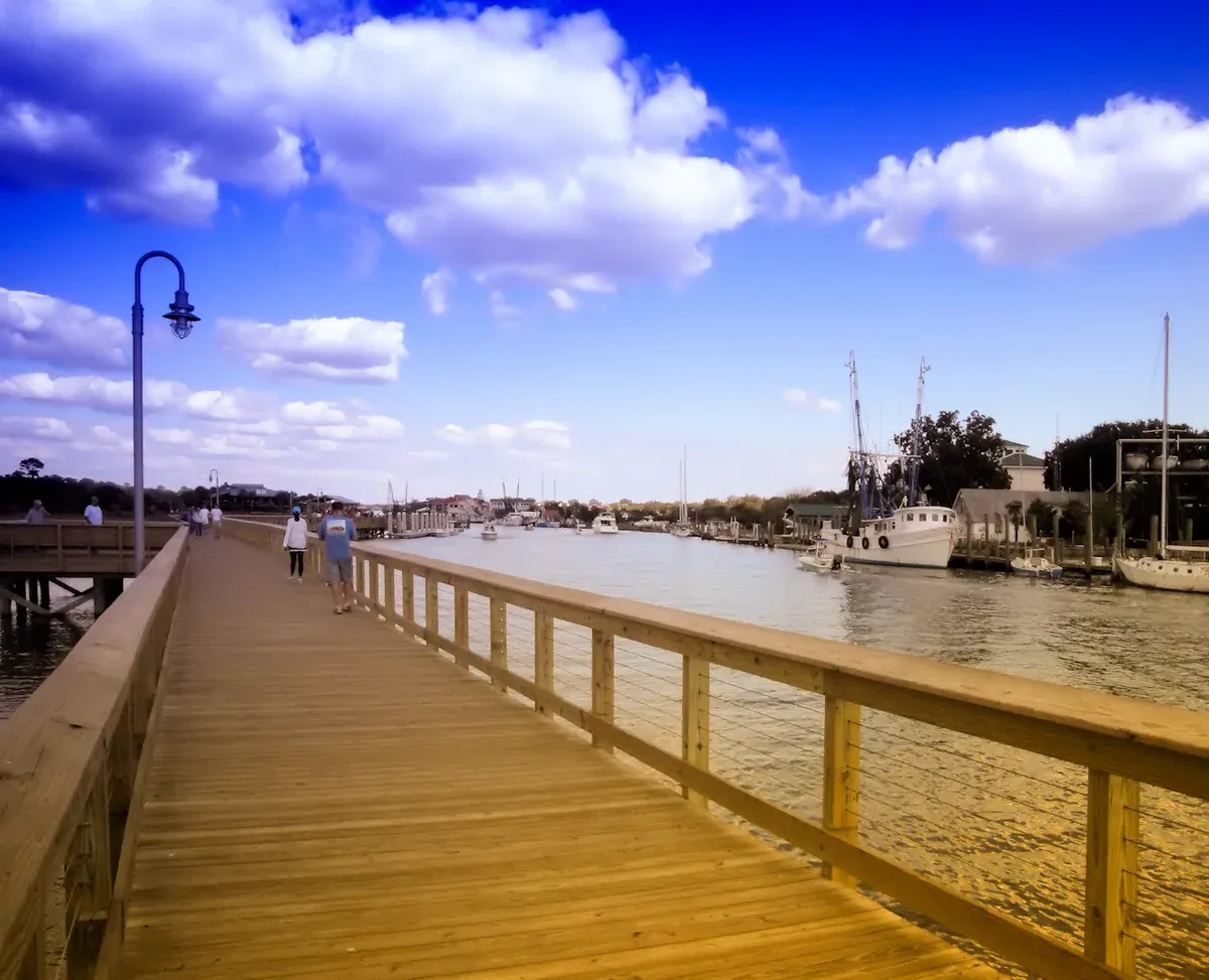 Wooden boardwalk beside moored boats on Shem Creek near Mount Pleasant, Charleston catamaran sunset cruise area